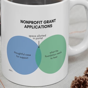 May include: A white ceramic mug featuring a black text graphic titled NONPROFIT GRANT APPLICATIONS. The design includes a blue and green Venn diagram with labels reading thoughtful case for support, space allotted in portal, and what the foundation needs to hear.