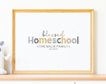 May include: A framed print with the text "blessed Homeschool" in a stylized font with gray and gold accents. The text "THE MALIK FAMILY est 2023" is below the main text.