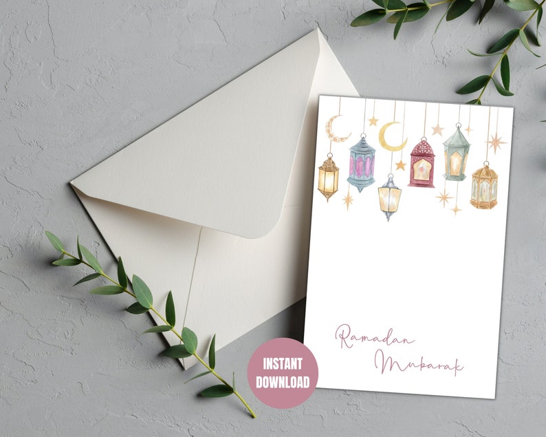 May include: Printable Ramadan Mubarak card with a white background and a string of colorful lanterns with gold stars and crescent moons. The text "Ramadan Mubarak" is written in pink cursive.