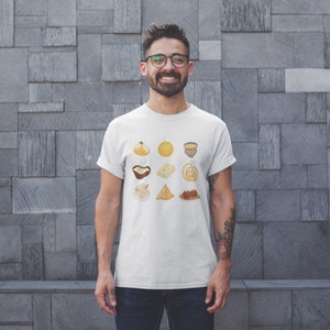 Op de afbeelding: Een wit T-shirt met een afbeelding van negen verschillende Indiase zoetigheden en snacks. De afbeelding is in een rasterpatroon gerangschikt en toont een verscheidenheid aan kleuren en texturen.