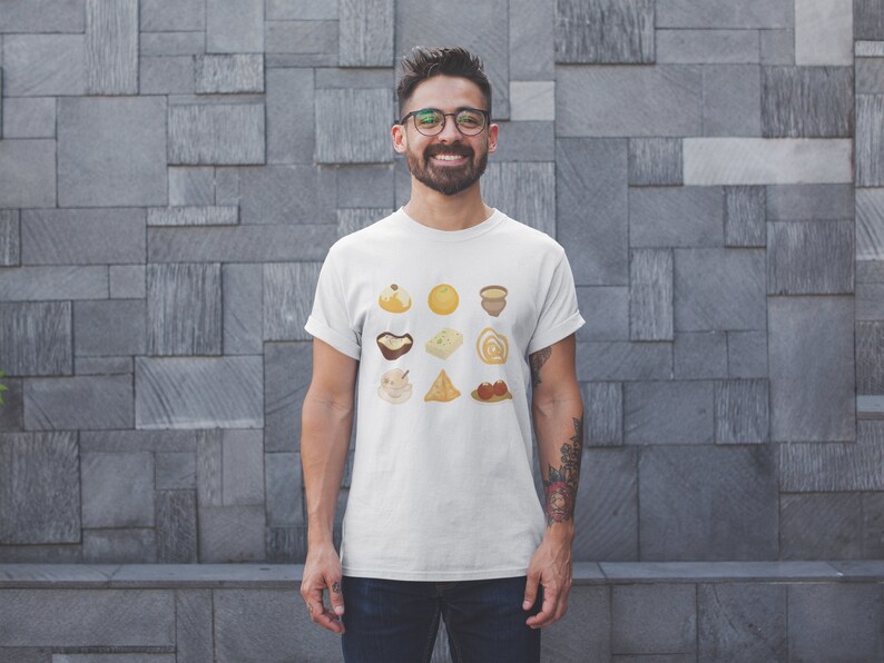 Op de afbeelding: Een wit T-shirt met een afbeelding van negen verschillende Indiase zoetigheden en snacks. De afbeelding is in een rasterpatroon gerangschikt en toont een verscheidenheid aan kleuren en texturen.