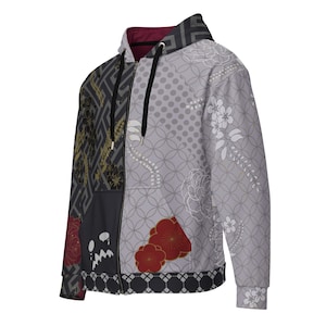May include: A zip-up hoodie with a unique patchwork design. The left side features a dark grey geometric pattern with gold accents, while the right side has a grey floral and dot pattern. Red floral accents and a black trim complete the design.