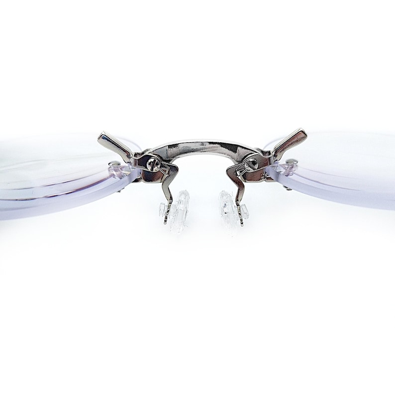 May include: A pair of silver-toned clip-on reading glasses with clear lenses. The glasses have a spring-loaded hinge and are designed to attach to existing eyeglasses.