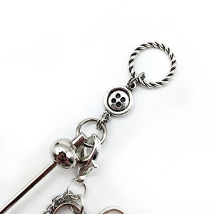 May include: Silver charm bracelet with a button charm, a twisted rope charm, and a small ball charm.