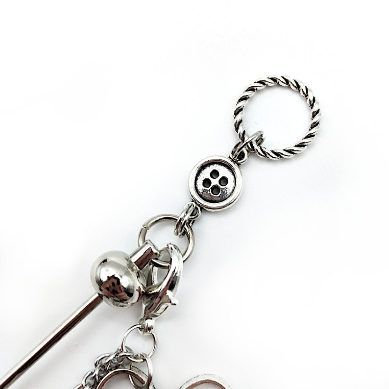 May include: Silver charm bracelet with a button charm, a twisted rope charm, and a small ball charm.
