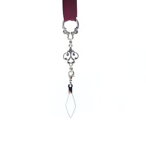 Pode incluir: Um marcador de livro de fita bord&ocirc; com um berloque decorativo prateado. O berloque apresenta um design ornamentado com um fecho de lagosta e um fio em forma de diamante. O marcador de livro est&aacute; sobre um fundo branco.