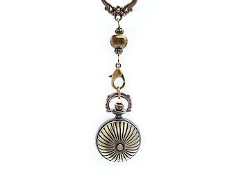May include: A gold-toned pocket watch with a decorative chain and a red ribbon.