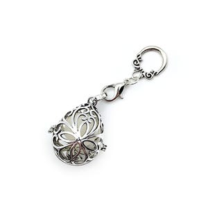 May include: A silver charm with a delicate, openwork design in the shape of a teardrop. The charm is attached to a silver chain with a lobster clasp.