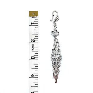 May include: Silver-toned threader with an ornate design, measuring approximately 3 inches in length. The threader has a hook at the top and a needle at the bottom.