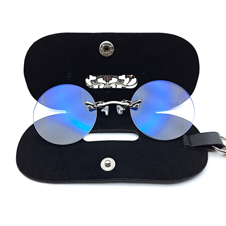 May include: A pair of blue tinted round glasses with a silver frame and a black leather case. The case has a silver clasp and a silver decorative piece on the front.
