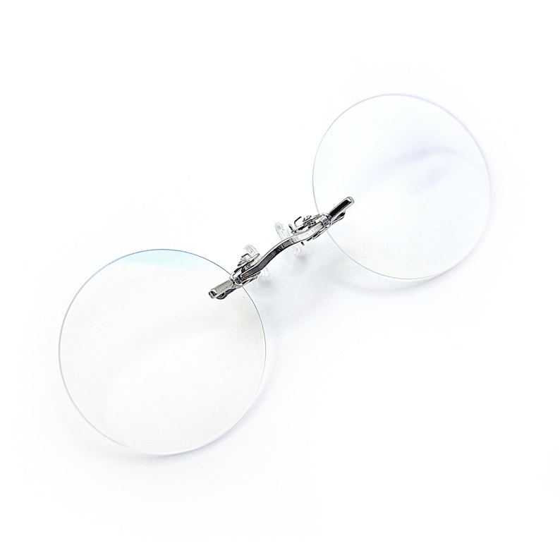 May include: A pair of silver-toned, round, rimless reading glasses with a spring hinge.