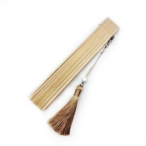 May include: A light brown hand fan with a white bead and a brown tassel attached to a silver chain.