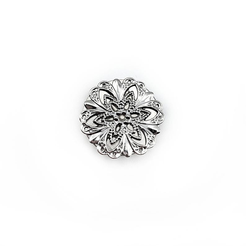 May include: Silver filigree flower brooch with a delicate, intricate design.