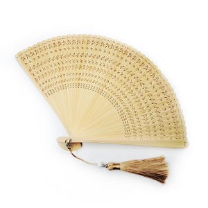 May include: A light brown bamboo hand fan with a delicate floral pattern and a brown tassel.