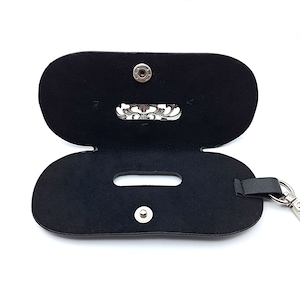 May include: Black leather case with a silver clasp and a silver chain. The case has a small pocket on the inside.