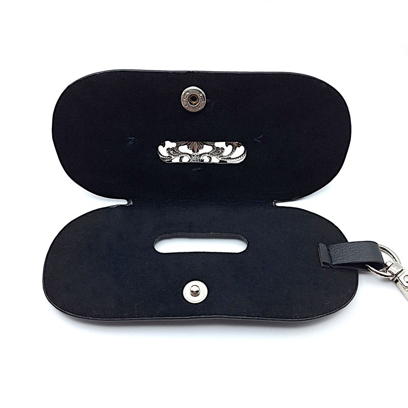 May include: Black leather case with a silver clasp and a silver chain. The case has a small pocket on the inside.