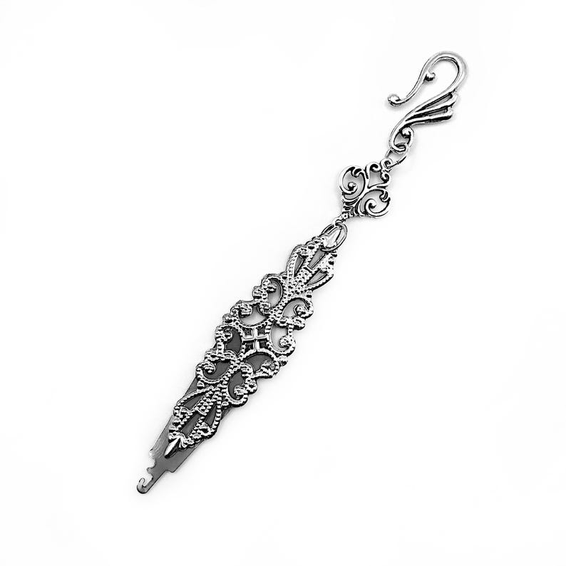 May include: Silver filigree bookmark with a decorative hook at the top. The bookmark is designed with intricate swirls and loops.