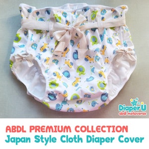 Può includere: Copertura per pannolino in tessuto bianco con una stampa di animali colorati che include elefanti, uccelli e cavalli. La copertura ha una fascia elastica bianca e un fiocco di nastro beige. Il testo "Diaper-U abdl metaverse" è visibile nell'angolo in basso a destra.