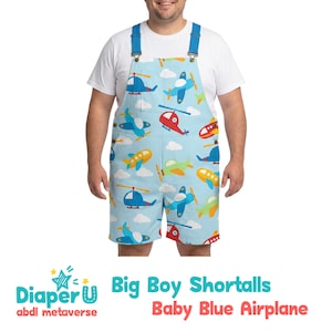 Op de afbeelding: Babyblauwe korte tuinbroek met een patroon van kleurrijke vliegtuigen en helikopters. De tuinbroek heeft blauwe bandjes en de tekst "Big Boy Shortalls Baby Blue Airplane" is erop gedrukt, samen met het "Diaper U" logo.