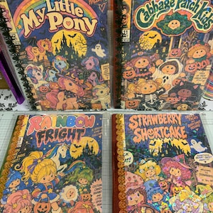 May include: Four comic books featuring My Little Pony, Cabbage Patch Kids, Rainbow Fright, and Strawberry Shortcake with Halloween themes. Each cover displays colourful characters, pumpkins, ghosts, and haunted houses in a festive, spooky style.
