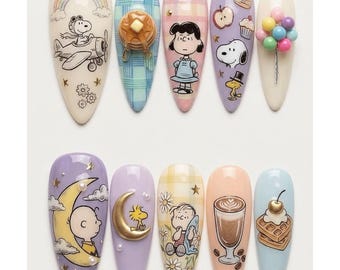 Könnte beinhalten: Ein Set aus zehn mandelförmigen Press-on-Nägeln mit Illustrationen der Peanuts-Figuren. Die Designs zeigen Snoopy im Flugzeug, Lucy, Woodstock, Charlie Brown auf dem Mond, Pfannkuchen, Waffeln, Kaffee sowie bunte 3D-Ballon-Akzente und Goldsterne.