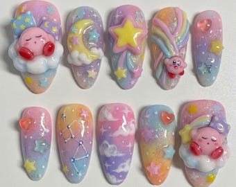 Könnte beinhalten: Ein Set aus zehn mandelförmigen Kunstnägeln mit einem verträumten Pastellthema. Jeder Nagel weist einzigartige Designs auf, darunter Sterne, Monde, Wolken und eine Cartoonfigur. Die Farbpalette umfasst Rosa, Blau, Gelb und Lila und erzeugt eine skurrile und verspielte Ästhetik.
