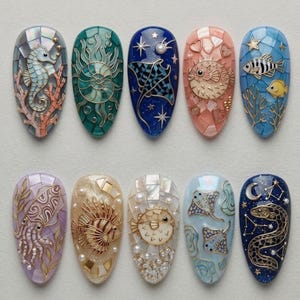 May include: Ten almond-shaped nail art tips featuring intricate marine-themed designs. Each tip displays a unique mosaic background with raised gold-toned metal accents depicting sea creatures including a seahorse, pufferfish, squid, and stingrays.