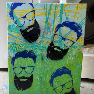 May include: Abstract art canvas featuring four stylized portraits of men with glasses and beards. The portraits are in blue and black, set against a background of green, yellow, and blue paint splatters.