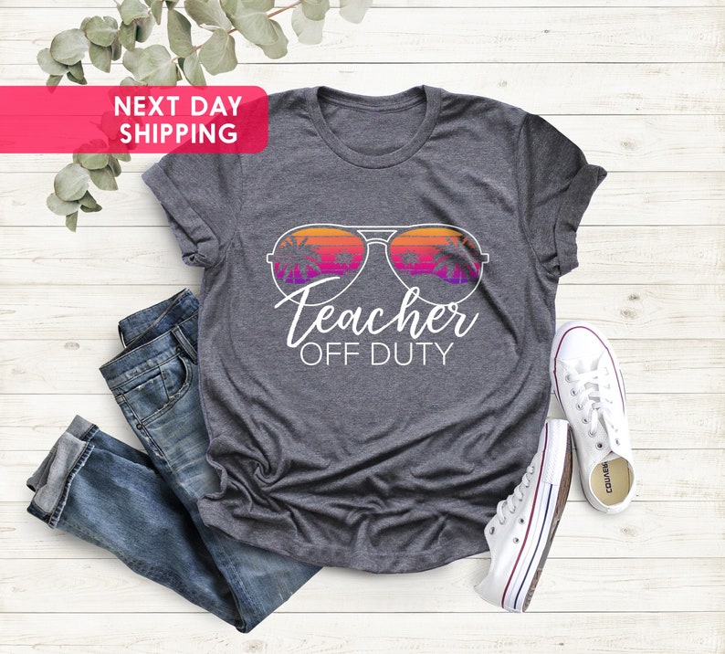 May include: Gray t-shirt with a graphic of sunglasses with palm trees reflected in the lenses. The text "Teacher Off Duty" is below the sunglasses.