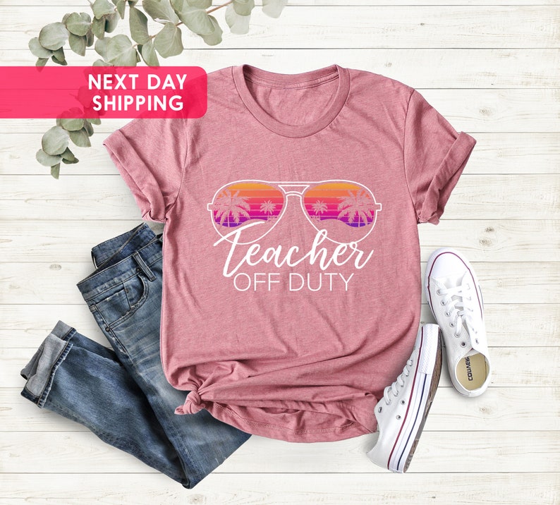 May include: A pink t-shirt with a white graphic of sunglasses with palm trees reflected in the lenses. The text "Teacher Off Duty" is below the sunglasses.