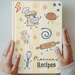 Puede incluir: Un cuaderno de recetas de tapa dura con rayas verticales de color amarillo pálido y blanco. La portada presenta ilustraciones de una batidora, pan, mangas pasteleras, un rodillo y un batidor, con el texto Monica's Recipes impreso.