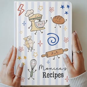 Puede incluir: Un cuaderno de recetas de tapa dura con rayas verticales de color azul claro y blanco. La portada presenta ilustraciones de dibujos animados de una batidora, pan, mangas pasteleras, un rodillo y un batidor, con el texto Monica's Recipes en negro.