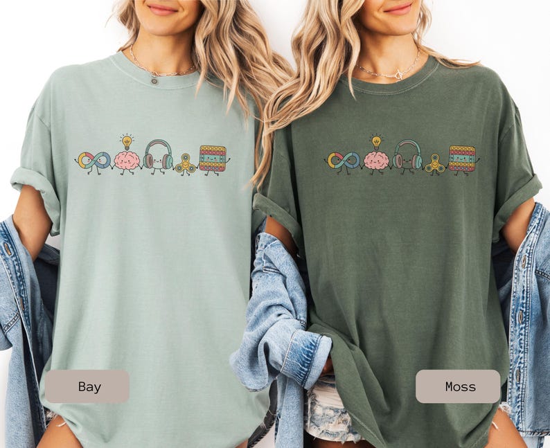 Comfort Colors Autism Doodle Characters Shirt featuring colorful, hand-drawn inclusive characters. Neatly styled next to classroom supplies, making it an ideal inclusion shirt, autism teacher shirt, and back to school shirt.