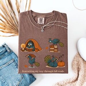 Comfort Colors shirt with whimsical peacock illustrations reading books, paired with pumpkins and cozy fall designs, perfect book lover tee.
Book Lover Comfort Colors Tee.nautumn gift for bookworms, librarians, teachers, and peacock lovers.
peacock shirt, funny peacock tee, peacock lover gift, book lover shirt, fall reading shirt, comfort colors tee, bookish shirt, librarian gift, cute peacock shirt, autumn book shirt, teacher gift tee, book club shirt, cozy fall shirt