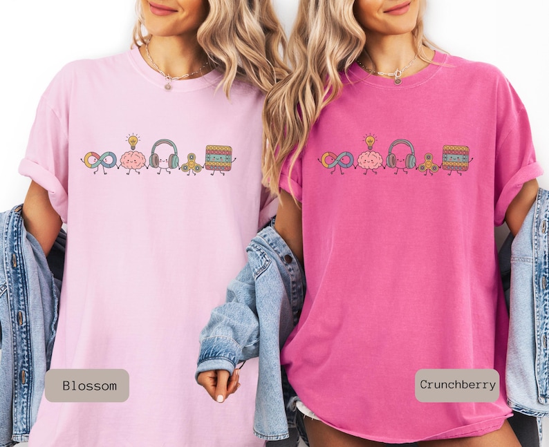 Comfort Colors Autism Doodle Characters Shirt featuring colorful, hand-drawn inclusive characters. Neatly styled next to classroom supplies, making it an ideal inclusion shirt, autism teacher shirt, and back to school shirt.