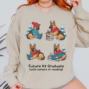 Future K9 Graduate Sweatshirt. This cozy German Shepherd shirt features four cute German Shepherds reading books, making it a perfect dog lover gift. It's an ideal bookish jumper and a great Xmas gift for dog moms and dog dads who love reading. This holiday sweatshirt is a funny and charming way to celebrate a love for dogs and books during the winter holiday season.