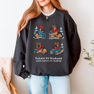 Future K9 Graduate Sweatshirt. This cozy German Shepherd shirt features four cute German Shepherds reading books, making it a perfect dog lover gift. It's an ideal bookish jumper and a great Xmas gift for dog moms and dog dads who love reading. This holiday sweatshirt is a funny and charming way to celebrate a love for dogs and books during the winter holiday season.