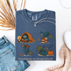 Comfort Colors shirt with whimsical peacock illustrations reading books, paired with pumpkins and cozy fall designs, perfect book lover tee.
Book Lover Comfort Colors Tee.nautumn gift for bookworms, librarians, teachers, and peacock lovers.
peacock shirt, funny peacock tee, peacock lover gift, book lover shirt, fall reading shirt, comfort colors tee, bookish shirt, librarian gift, cute peacock shirt, autumn book shirt, teacher gift tee, book club shirt, cozy fall shirt