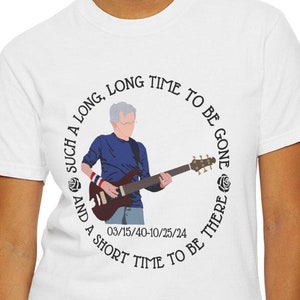 May include: White t-shirt featuring a circular graphic with a musician playing a guitar. The graphic includes the text "SUCH A LONG, LONG TIME TO BE GONE AND A SHORT TIME TO BE THERE" and the numbers "03/15/40-10/25/24".