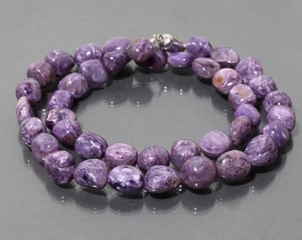 May include: A purple and white gemstone necklace made of oval-shaped beads. The necklace is made of natural stones and is approximately 18 inches long.