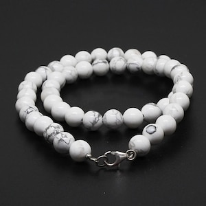 Puede incluir: Collar de cuentas de howlite blanco con cierre de plata. Las cuentas son redondas y tienen un patrón de mármol.