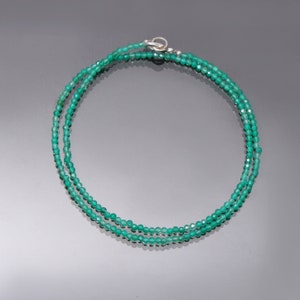 Puede incluir: Un delicado collar de piedras preciosas verdes con un cierre de plata. El collar está hecho de pequeñas cuentas facetadas y está en capas para un look sutil y elegante.