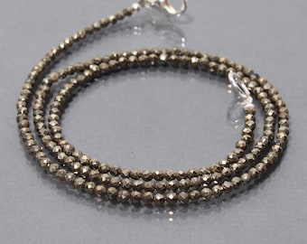 Puede incluir: Un collar dorado hecho de pequeñas cuentas de pirita facetadas. El collar mide aproximadamente 45 cm de largo y tiene un cierre de plata.