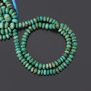 Könnte beinhalten: Eine Strähne grüner Türkis-Edelsteinkugeln. Die Kugeln sind oval geformt und haben eine gefleckte grüne Farbe.