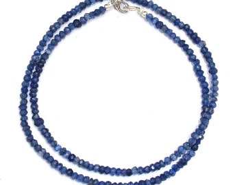 May include: A double strand necklace made of blue gemstone beads. The beads are faceted and have a slightly irregular shape. The necklace is secured with a silver clasp.