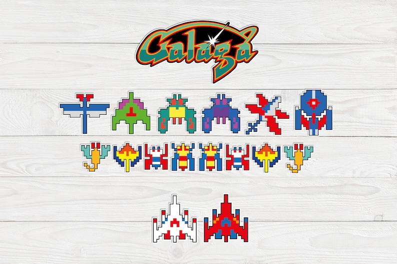 Colourful Galaga arcade game stickers. 17 individual characters and Galaga logo stickers pictured on a white wooden board background. Space ships and aliens. 1980s retro arcade game stickers. Nostalgic 1980s feel.