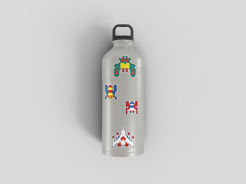 4 colourful Galaga arcade character stickers pictured stuck to a grey drinking bottle. 1980s retro arcade game stickers. Nostalgic 1980s feel.