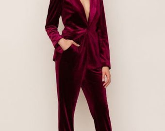 May include: A burgundy velvet blazer and pants set. The blazer has a deep V-neck and long sleeves. The pants are slim-fitting and have a straight leg.