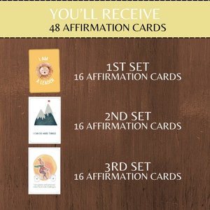 K&ouml;nnte beinhalten: Ein Set mit 48 Affirmationskarten, aufgeteilt in drei Sets mit jeweils 16 Karten. Die Karten zeigen farbenfrohe Illustrationen und positive Affirmationen. Die erste Karte zeigt einen L&ouml;wen mit dem Text "Ich bin ein Anf&uuml;hrer". Die zweite Karte zeigt Berge mit dem Text "Ich kann schwierige Dinge tun". Die dritte Karte zeigt ein Kaninchen, das Fahrrad f&auml;hrt, mit dem Text "Ich bin geduldig und ausdauernd, wenn ich mit Herausforderungen konfrontiert werde".