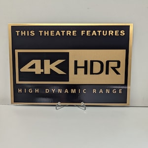 May include: Gold plaque with black text that reads "This theatre features 4K HDR High Dynamic Range".